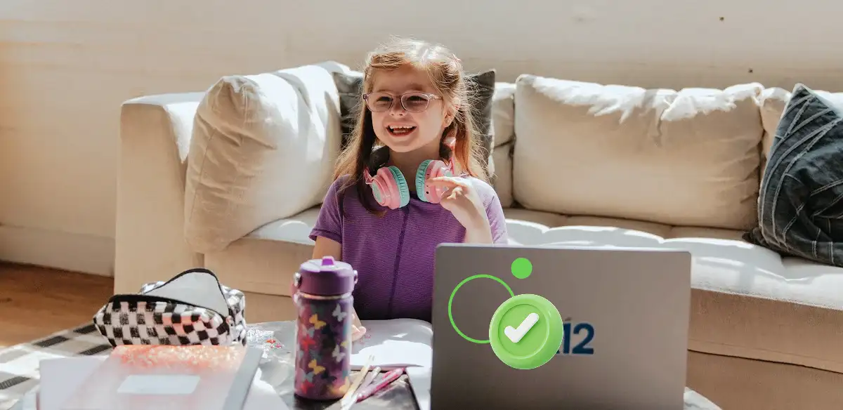 Elementary student working with her laptop at home wearing a pink pair of headphones